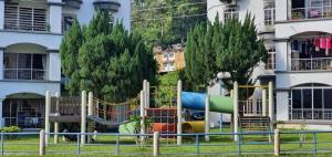 a playground in front of a building with trees at Hilltop Greenview Residence Batu Caves Selayang in Batu Caves
