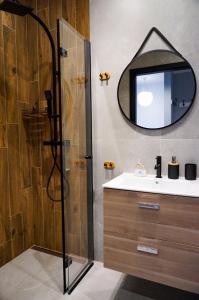 a bathroom with a shower and a sink and a mirror at Słoneczny Apartament in Ustronie Morskie