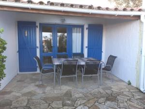 a table and chairs on a patio with blue doors at Résidence Sables d'Or Accès direct plage in La Guérinière