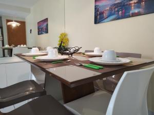 einem Holztisch mit Tellern und Utensilien darauf in der Unterkunft Flat térreo Palm Village Acqua Porto de Galinhas in Porto De Galinhas