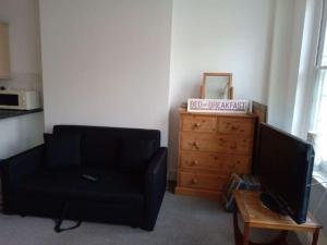 sala de estar con sofá negro y cómoda en Lovely 1-bedroom flat within minutes from the beach!, en Bexhill-on-Sea