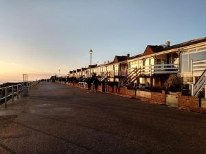 a group of people walking down a street next to buildings at Lovely 1-bedroom flat within minutes from the beach! in Bexhill