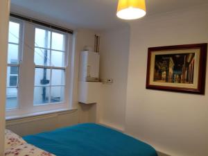 sypialnia z niebieskim łóżkiem i oknem w obiekcie Lovely 1-bedroom flat within minutes from the beach! w mieście Bexhill