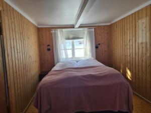 a small bedroom with a bed and a window at Lite hus ved sjøen 