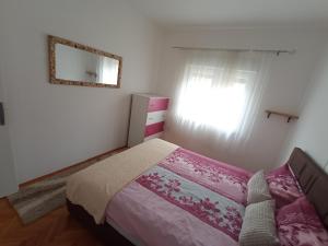 a bedroom with a bed and a mirror and a window at Apartman Maja in Trebinje