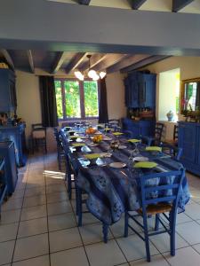 a dining room with a long table and blue cabinets at Chambres d'Hôtes Le Relais du Passage de la Roche in Le Mesnil-sous-Jumièges