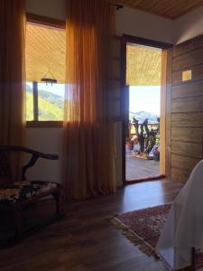 a bedroom with a large window with a view of a mountain at Hospedaria Sol & Lua in São Bento do Sapucaí