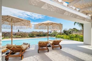 a patio with chairs and umbrellas next to a swimming pool at Gatsby Rhodes-Brand New Seaview Villa in Asgourou