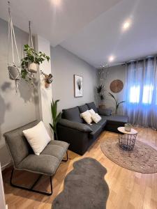 ein Wohnzimmer mit einem schwarzen Sofa und Stühlen in der Unterkunft Apartamenro A Tixola casco histórico in Pontevedra