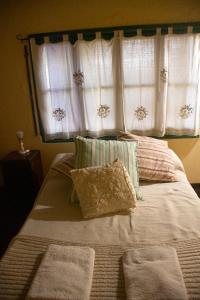 a bed with two pillows and two windows at La Finca de Buen Orden in San Martín