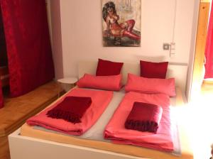 een bed met rode lakens en kussens erop bij Atelier Mariaberg in Kempten