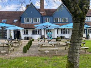 un bâtiment avec des tables de pique-nique et des parasols bleus dans l'établissement Hockley House, à Hockley Heath