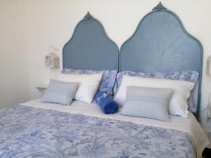 a bed with a blue headboard and white pillows at Saja Country House in Acireale