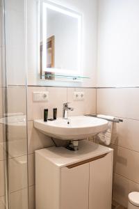 La salle de bains blanche est pourvue d'un lavabo et d'un miroir. dans l'établissement Wetterstein, à Oberstaufen