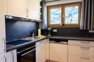 uma cozinha com armários brancos, um lavatório e uma janela em Thaler Höhe em Oberstaufen