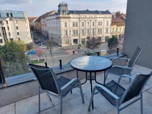 d'une table et de chaises sur un balcon avec vue sur un bâtiment. dans l'établissement NoMi Ultracentral Apartments, à Târgu-Mureş
