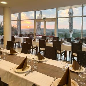 un restaurant avec des tables blanches, des chaises et des fenêtres dans l'établissement Hotel Kozana, à Dobrovo