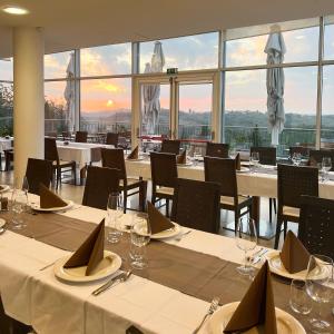 un ristorante con tavoli e sedie bianchi e finestre di Hotel Kozana a Dobrovo
