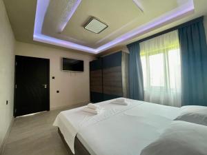 - une chambre avec un grand lit blanc et une télévision dans l'établissement Къща за гости ЕМ Парадайс, à Tserova Koriya