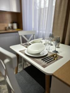- une table avec une assiette blanche et des verres à vin dans l'établissement Nursultana Nazarbaeva 20 Str by Slissenko Inn, à Pavlodar