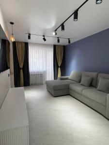 a living room with a couch and a blue wall at Nursultana Nazarbaeva 20 Str by Slissenko Inn in Pavlodar
