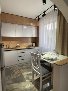 uma cozinha com uma mesa com cadeiras e um lavatório em Nursultana Nazarbaeva 20 Str by Slissenko Inn em Pavlodar
