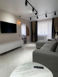 a living room with a couch and a flat screen tv at Nursultana Nazarbaeva 20 Str by Slissenko Inn in Pavlodar