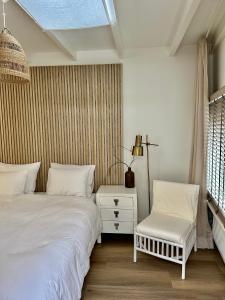 a bedroom with two beds and a chair at Oranje Nassau aan Zee Studio in Zandvoort