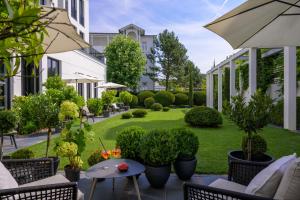 an outdoor patio with chairs and a lawn with plants at A-ROSA Collection Hotel Ceres am Meer in Binz