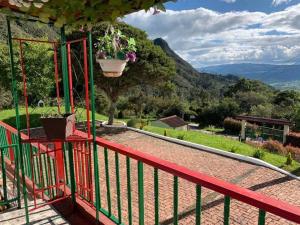 un balcón de madera roja con una maceta de flores. en Hotel Cerro Fuerte Sopó, en Sopó