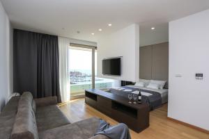 a bedroom with a bed and a couch and a television at Apartments Lux sea view in Budva