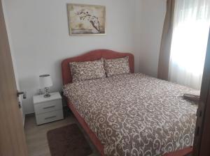 een slaapkamer met een bed met een bruine sprei en een raam bij Andrea Airport Apartments in Belgrado