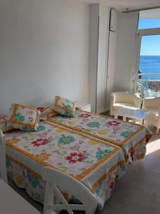 um quarto com uma cama com colcha floral e uma janela em Canalex em Maspalomas