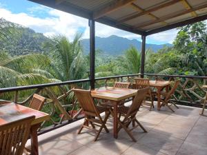 a patio with tables and chairs and mountains in the background at Serenity Lodges Dominica in Marigot