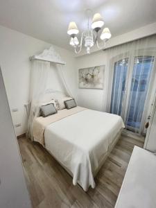 Habitación blanca con cama blanca y lámpara de araña. en Maison Mele Ischia en Ischia