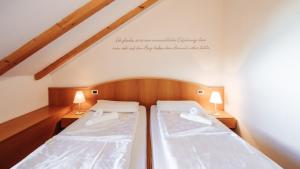 2 Betten in einem Zimmer mit zwei Lampen auf beiden Seiten in der Unterkunft Hotel Corno Bianco in Deutschnofen