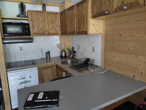 kuchnia z drewnianymi szafkami i białym blatem w obiekcie Appartement Valfréjus Thabor A pieds de pistes w mieście Modane