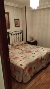 Un dormitorio con una cama con una manta. en La Perla de Candás, en Candás