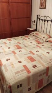 Una cama con edredón en un dormitorio en La Perla de Candás, en Candás
