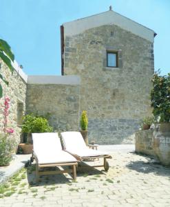 dos sillas blancas sentadas frente a un edificio de piedra en Villa Venetico stone retreat with garden, en Faneroméni