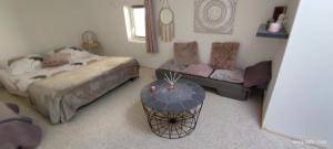 a bedroom with a bed and a couch and a table at Le cocoon de Christelle in Montredon