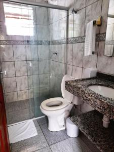 a bathroom with a toilet and a shower and a sink at Pousada Flores do Lázaro in Ubatuba