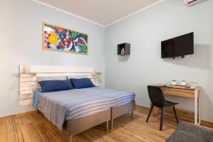 a bedroom with a bed and a desk and a television at RomeCookSea Guesthouse in Lido di Ostia