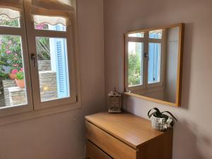 a bathroom with two windows and a wooden dresser at Karaoulanis Apartments in Andros