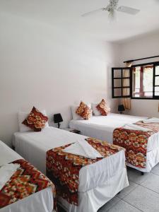 three beds in a room with white walls at Pousada Flores do Lázaro in Ubatuba