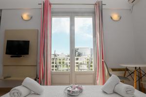 a room with a bed and a window and a television at Atrium Villa in Fira