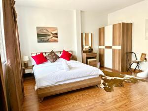 a bedroom with a large white bed with red pillows at Comfy Boutique House in Chiang Mai