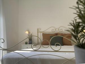 a white bedroom with a metal bed with plants at Casa Alva in Ragusa