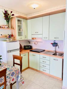 cocina con armarios blancos y mesa en Residence Tigli Campomarino, en Campomarino