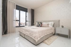 ein weißes Schlafzimmer mit einem Bett und einem Fenster in der Unterkunft jerusalem luxury apartment in Jerusalem